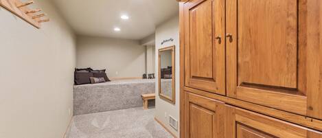 Un couloir avec une armoire en bois, un porte-manteau, un banc et un miroir accroché au mur.