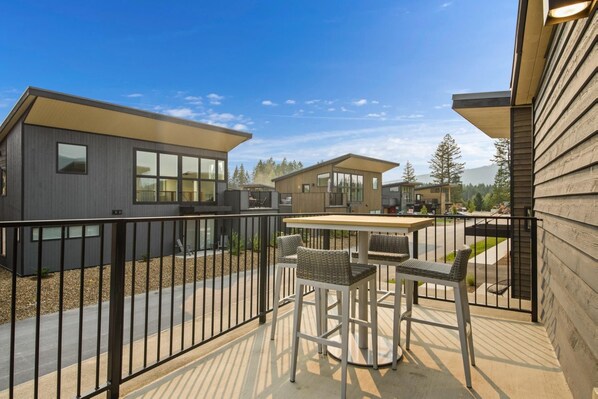 A modern residential area with multiple houses, a patio with outdoor furniture, and a clear view of the surrounding landscape.