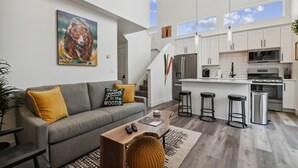 A modern kitchen with white cabinets, stainless steel appliances, and a bar area with stools. - Mountain Views and Clubhouse Access (Whitefish)