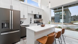 A modern kitchen with white cabinetry, stainless steel appliances, and a large island with bar stools.