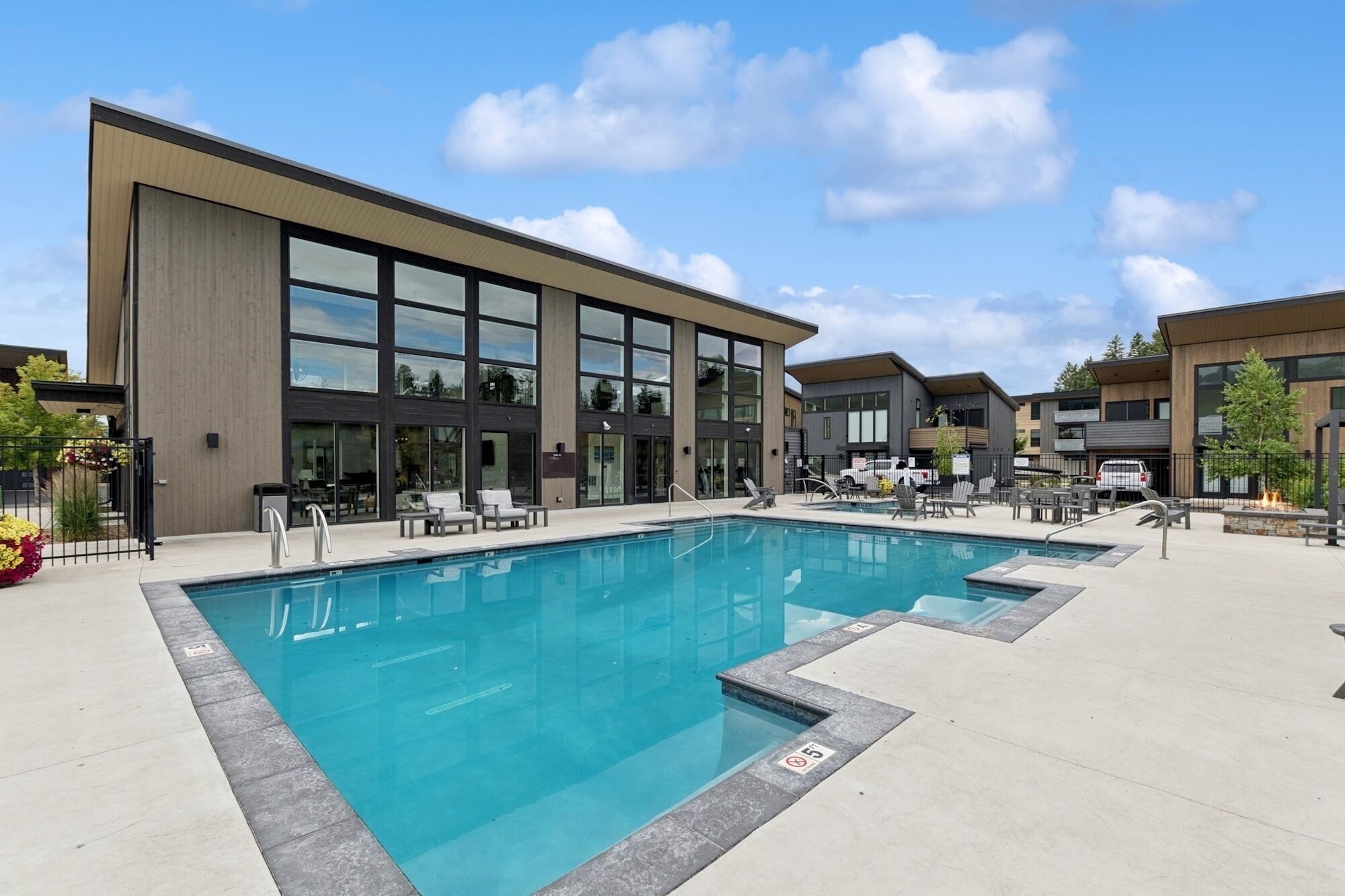 A modern outdoor swimming pool area with lounge chairs and a building with large windows.