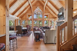 Un interior espacioso de madera con techos altos, ventanas grandes y una chimenea.
