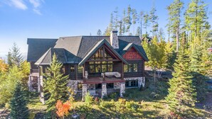 Eine Blockhütte mit Steinunterbau, einer großen Veranda und einem Schornstein.