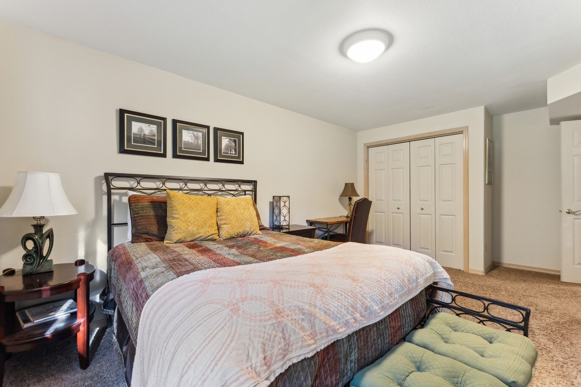 A bedroom with a bed, bedside tables, a lamp, a chair, a desk, and a wardrobe.