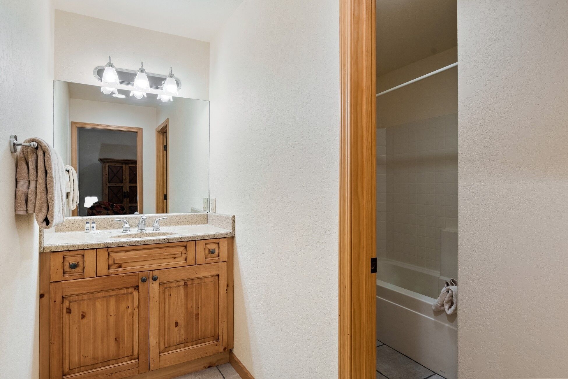 Une salle de bain avec un meuble-lavabo en bois, un grand miroir et un espace douche.