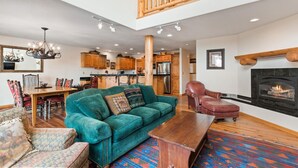A spacious living room with a green sofa, wooden coffee table, and a fireplace.