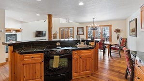 A spacious kitchen with a central island, wooden cabinets, a built-in oven, and a dining area with a chandelier.