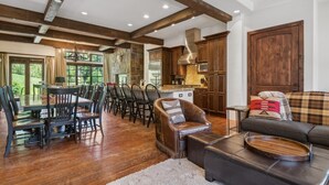 Amplia sala de estar con mesa y sillas de comedor, un sofá de cuero y una cocina con armarios de madera y chimenea de piedra.