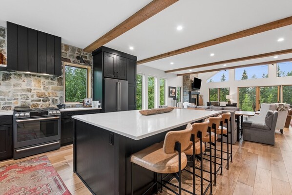 A modern kitchen with a large island, dark cabinetry, and a stone accent wall.