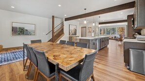 Une cuisine spacieuse dotée d’un îlot central, de planchers en bois et d’un escalier menant à un niveau supérieur.