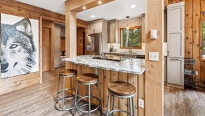 Une cuisine moderne avec des éléments en bois, un plan de travail en marbre et des tabourets de bar.