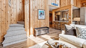 Un intérieur en bois comprenant un escalier, un coin cuisine et un salon avec un canapé et un objet décoratif.
