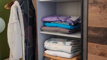 Ein Kleiderschrank mit mehreren Einlegeböden, gefüllt mit gefalteten Handtüchern und Decken in verschiedenen Farben und Mustern.