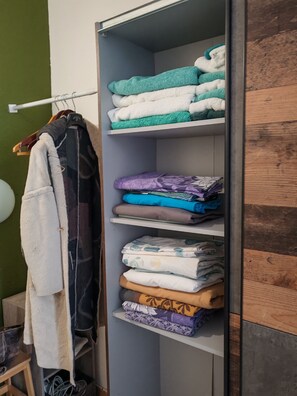 A closet with multiple shelves containing folded towels and blankets in various colors and patterns.
