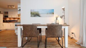 A modern kitchen with white cabinets, a wooden countertop, and a dining area with two chairs and a table. - Herzlich Willkommen in der Wohnung "diekleev"! (Büsum)