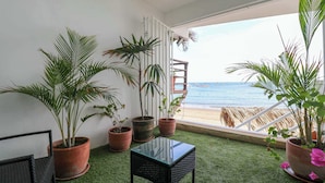 A balcony with potted plants, a glass table, and a view of the beach. - w* | Fascinating loft with Spectacular Ocean View (Máncora)