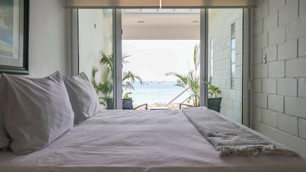 A bedroom with a large bed, a view of the beach, and a balcony with plants. - w* | Fascinating loft with Spectacular Ocean View (Máncora)