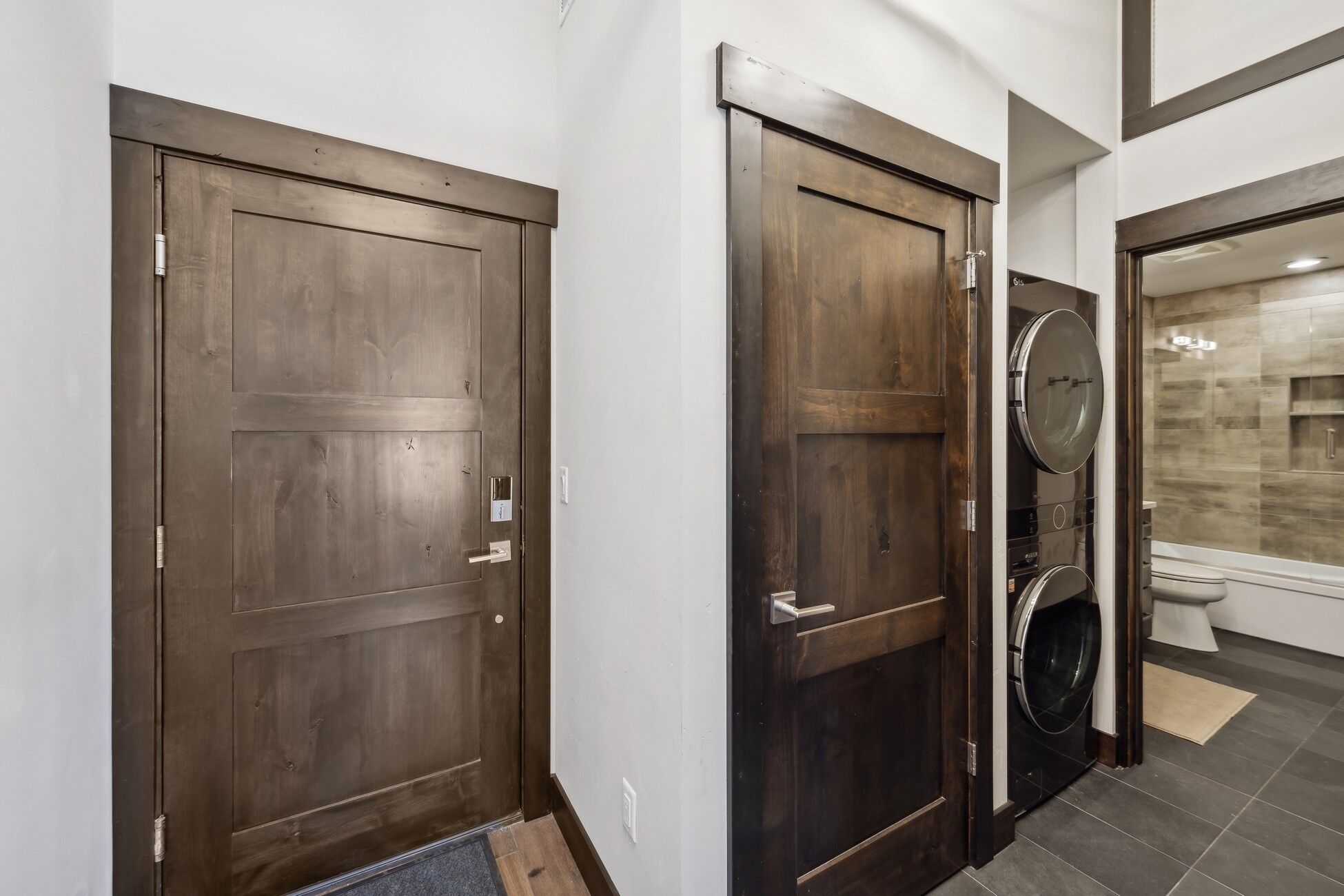 A hallway with two wooden doors, one of which has a built-in washer and dryer.