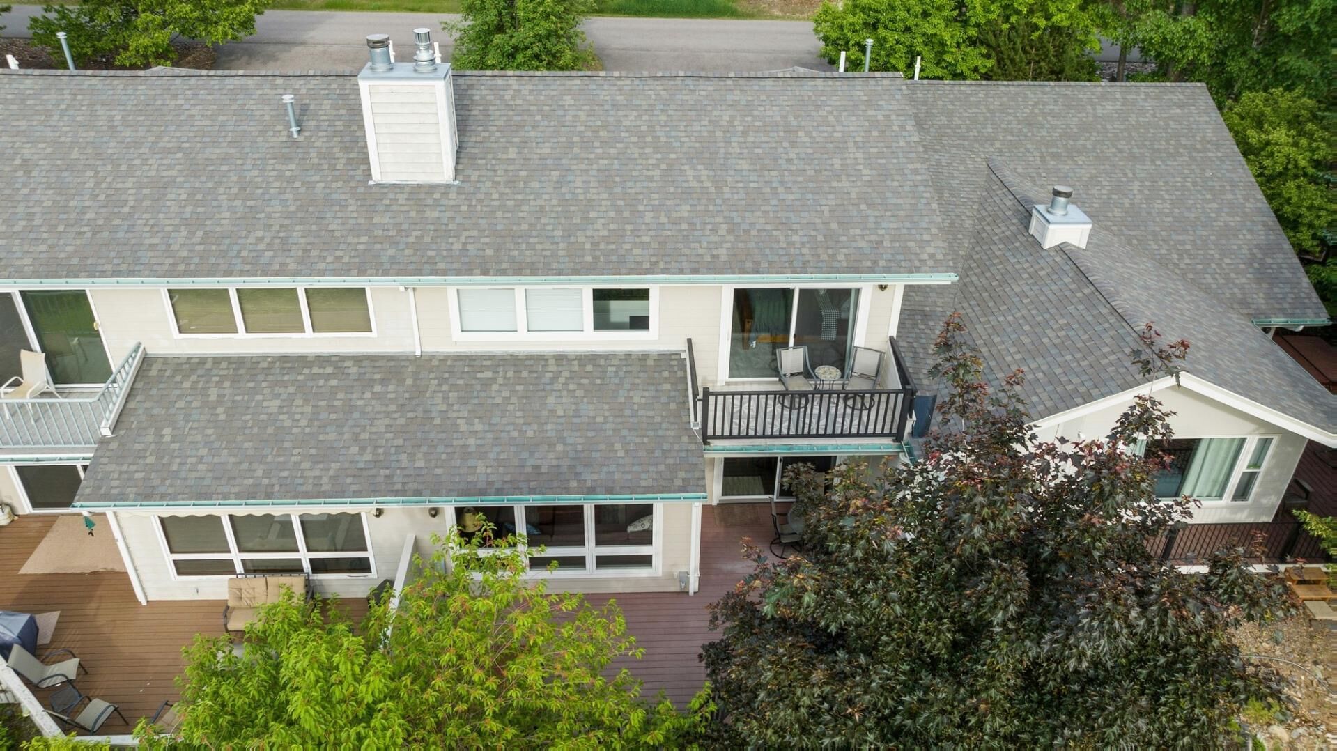 A two-story house with a balcony, large windows, and a chimney.