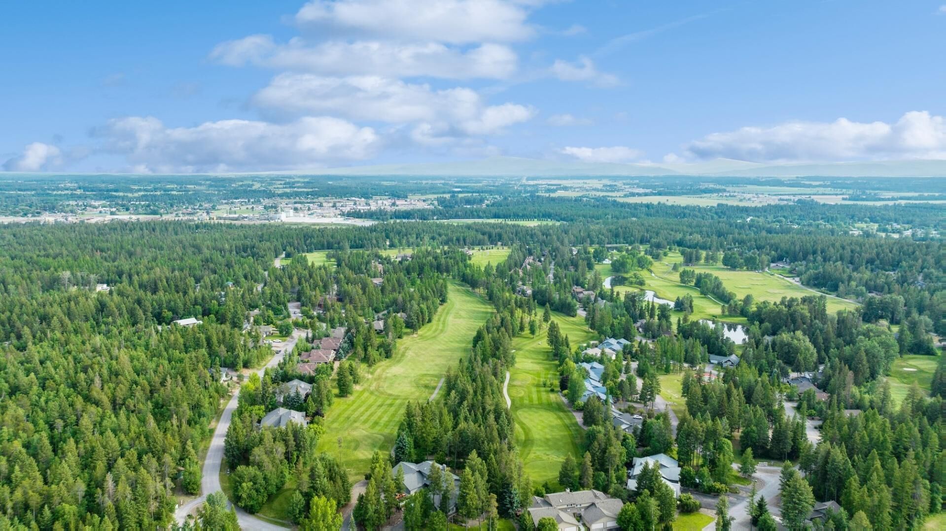 Ett bostadsområde med hus omgivna av täta skogar och golfbanor.