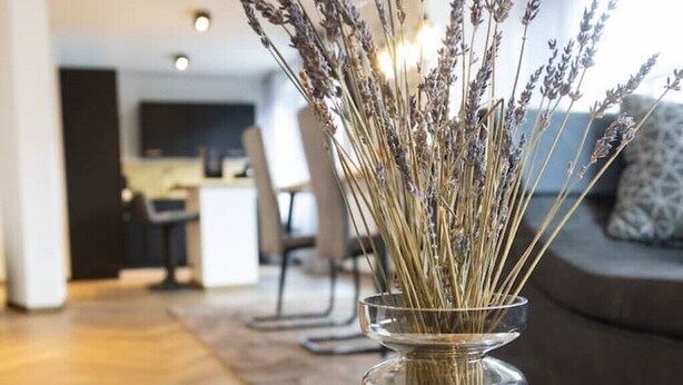 A clear vase with dried lavender on a marble table in a modern living room with a sofa and a TV in the background. - Stilvolle Stadtwohnung (Duisburg)
