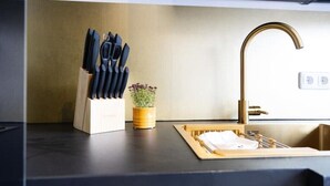 A kitchen counter with a knife block, a potted plant, and a sink with a gold faucet. - Stilvolle Stadtwohnung (Duisburg)