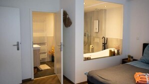 A bedroom with a large mirror, a bed, and a bathroom visible through an open door. - Stilvolle Stadtwohnung (Duisburg)