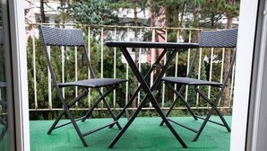 A balcony with two chairs and a table, surrounded by a metal railing. - Stilvolle Stadtwohnung (Duisburg)