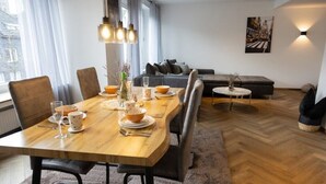 A dining area with a wooden table set for four, surrounded by chairs. There is a sofa and a small round table in the background. - Stilvolle Stadtwohnung (Duisburg)