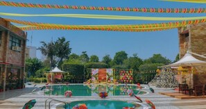 Ein Poolbereich mit Gazebo, einer Zierwand und einer Sitzgelegenheit.