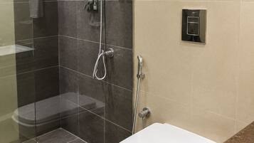 A modern bathroom with a glass-enclosed shower, a white toilet, and a granite countertop.