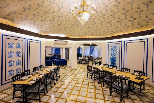A dining area with a checkered floor, tables set with chairs, and a chandelier.