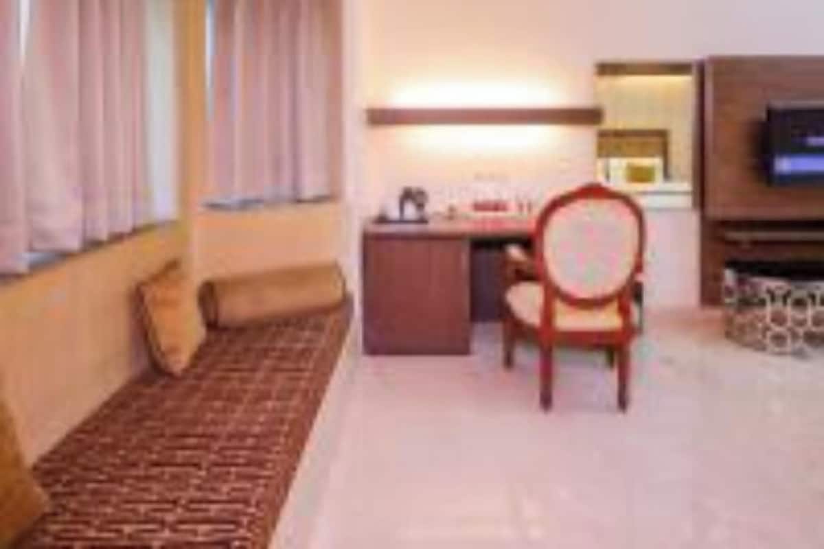 A hotel room with a bed, a desk, a chair, and a television.