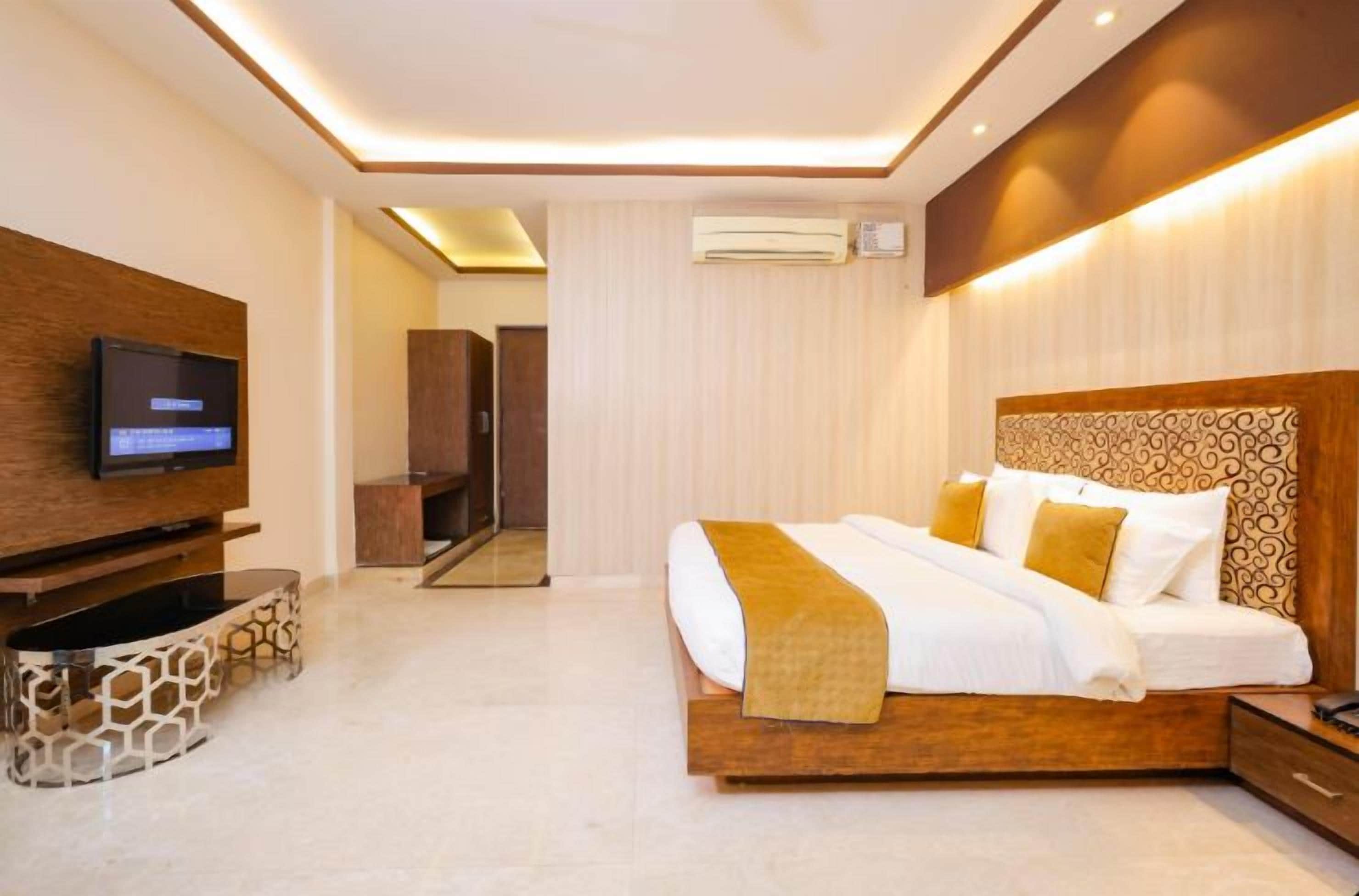 A modern hotel room with a large bed, a flat-screen TV, and a seating area with a unique design.