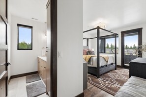 Un dormitorio moderno con cama con dosel, un baño pequeño con ventana y vistas al exterior.