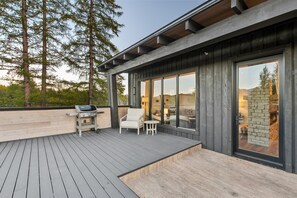 Een modern terras buiten met een barbecue, zitplaatsen en een stenen open haard.