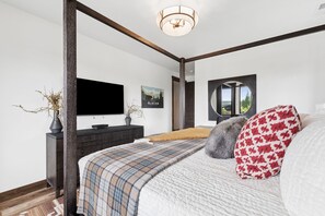 Une chambre à coucher avec un grand lit, un téléviseur à écran plat, un miroir et une fenêtre donnant sur un beau paysage.