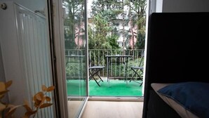 A balcony with a view of a green lawn and trees, a white radiator, and a black sofa. - Traumhafte Stadtwohnung (Duisburg)