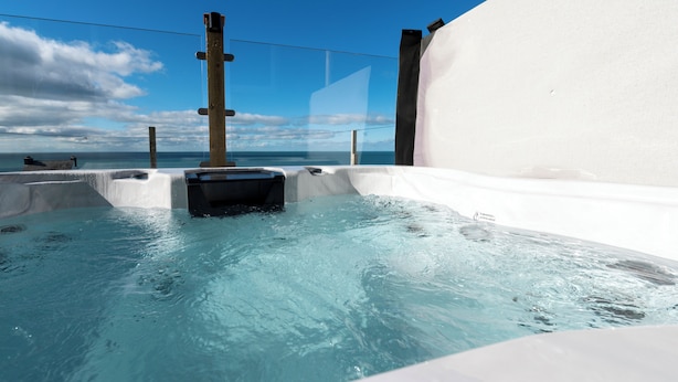 Ein Whirlpool mit freiem Blick auf den Ozean und einem Holzpfosten in der Mitte.