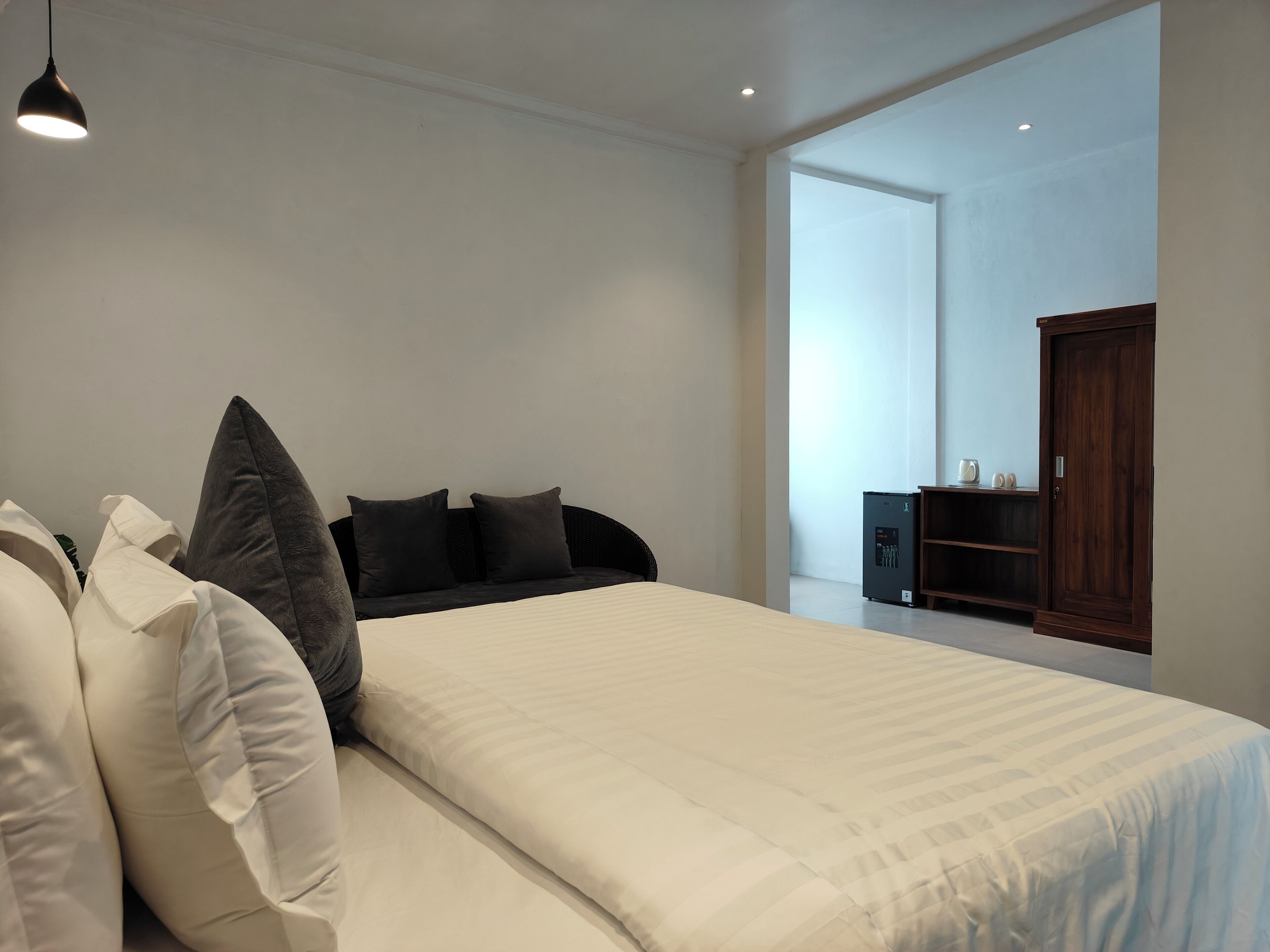 A bedroom with a bed, pillows, a wardrobe, and a small cabinet.