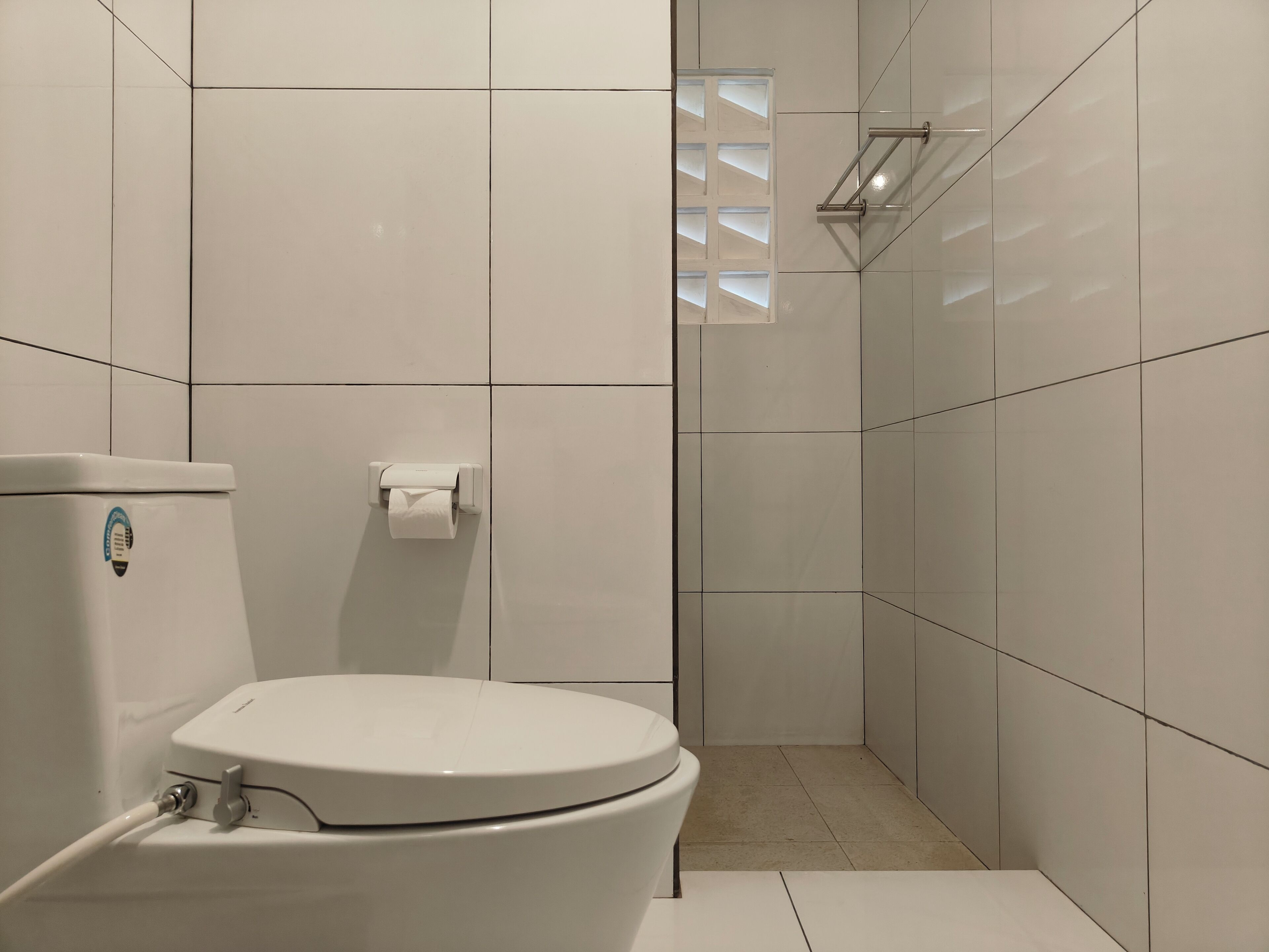 Un baño moderno con inodoro, dispensador de toallas de papel y zona de ducha.