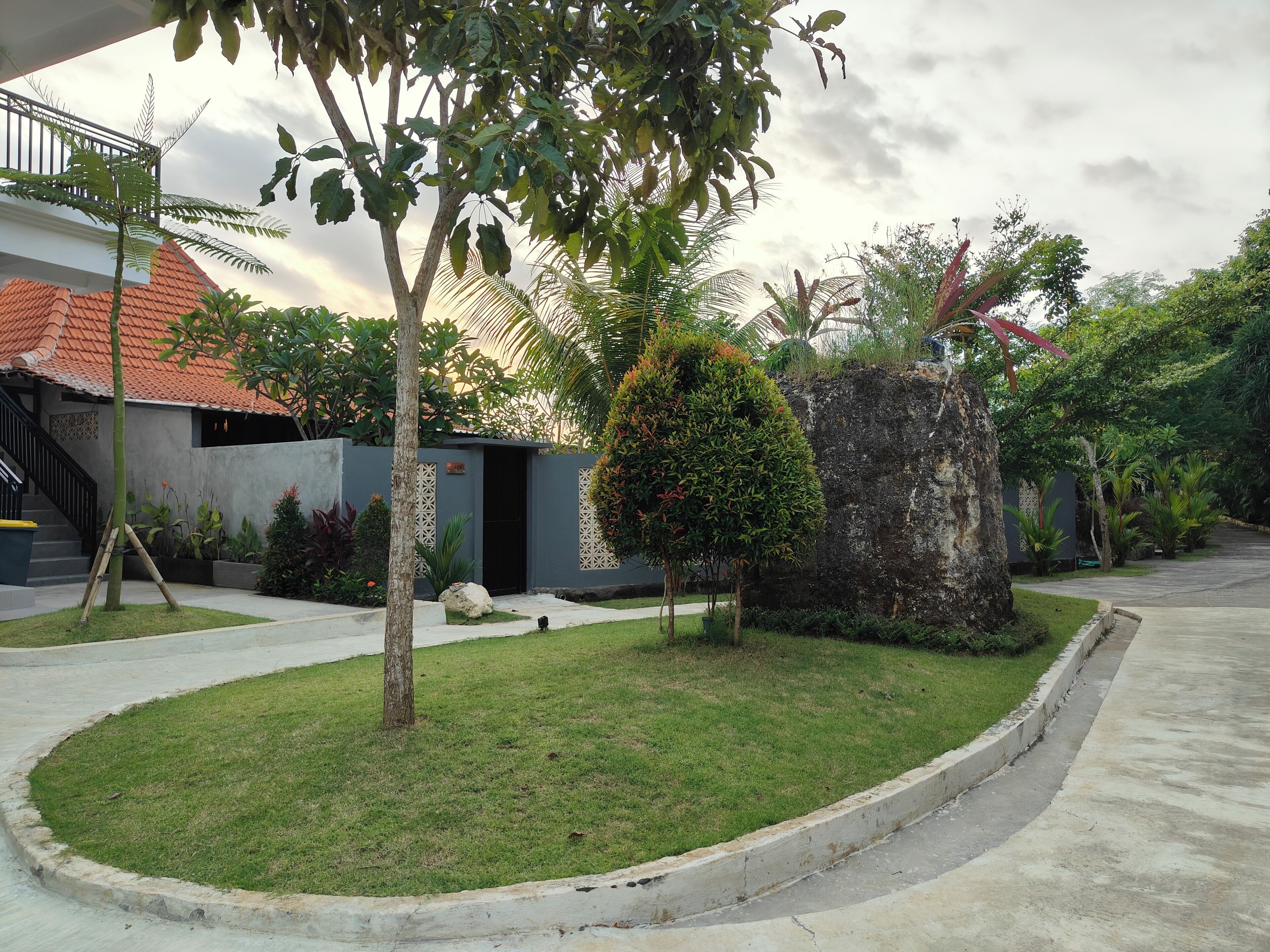 Un barrio residencial con un césped cuidado, un muro de piedra y una casa con tejado de tejas.