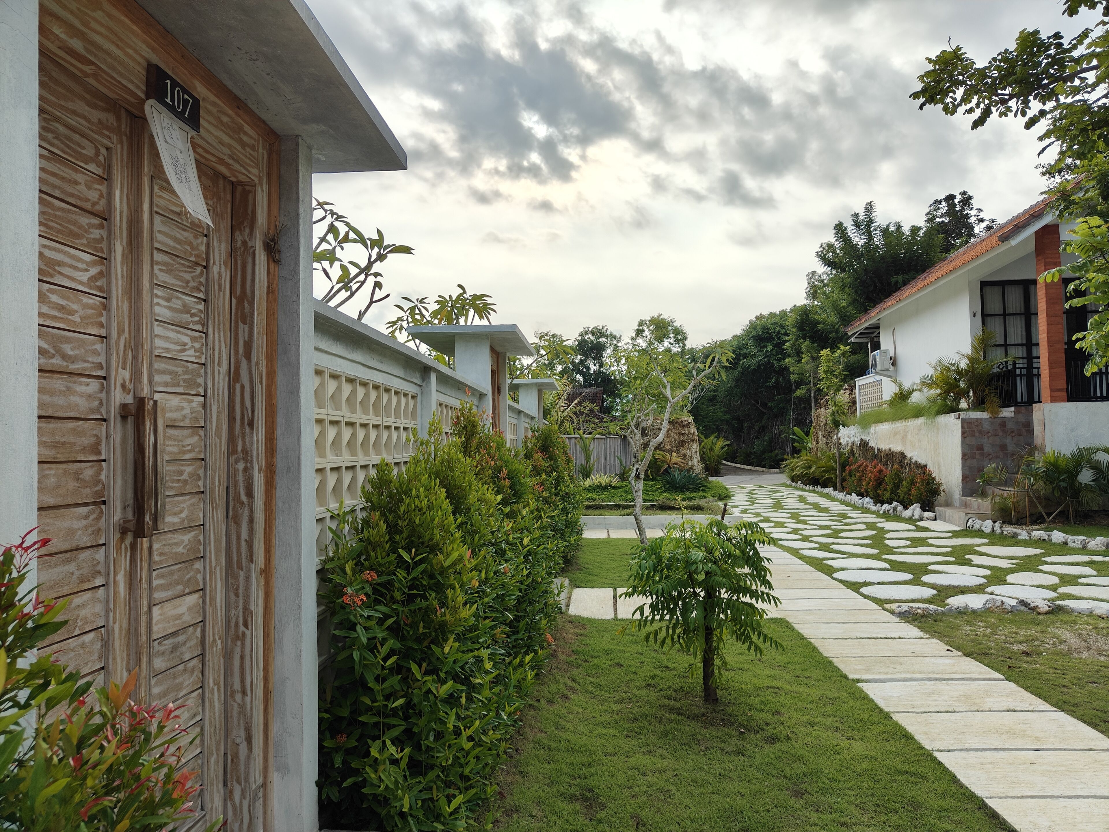 A residential property with a number 107 sign, a paved pathway, and a well-maintained garden.