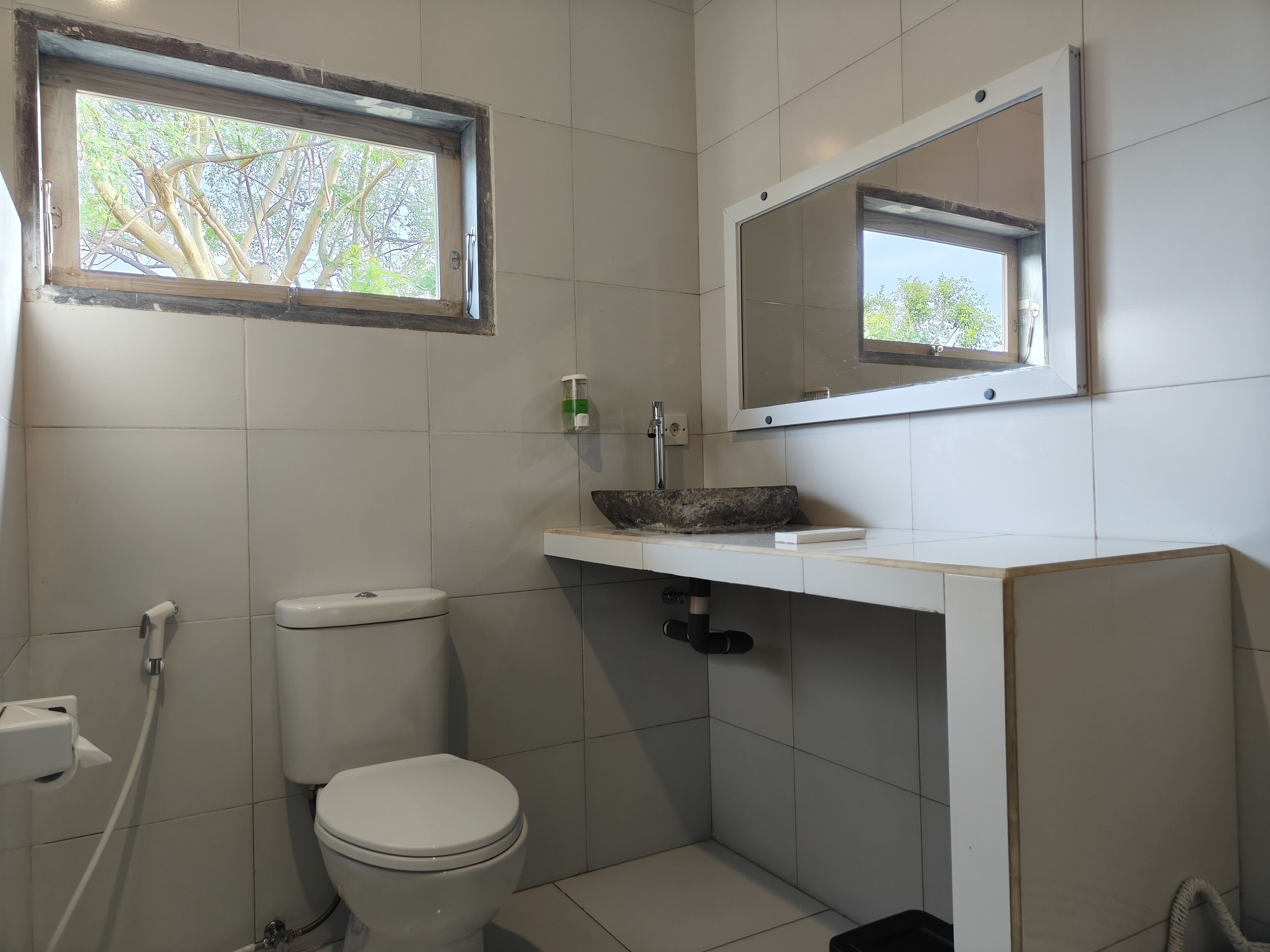 Une salle de bain avec des toilettes, un lavabo et une fenêtre.