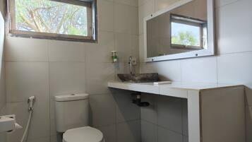 A bathroom with a toilet, sink, and window.