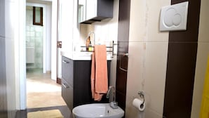 Un baño con inodoro, bidé, lavamanos y toallero.