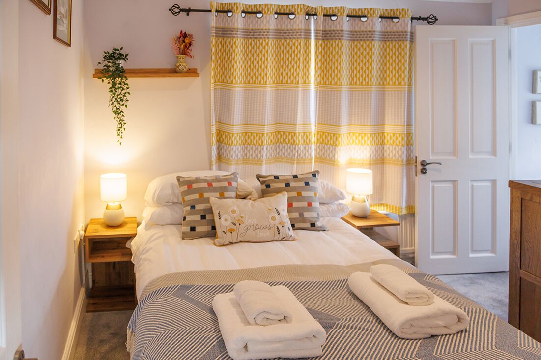 A neatly made bed with pillows, a bedside lamp, and a folded towel on the bed.