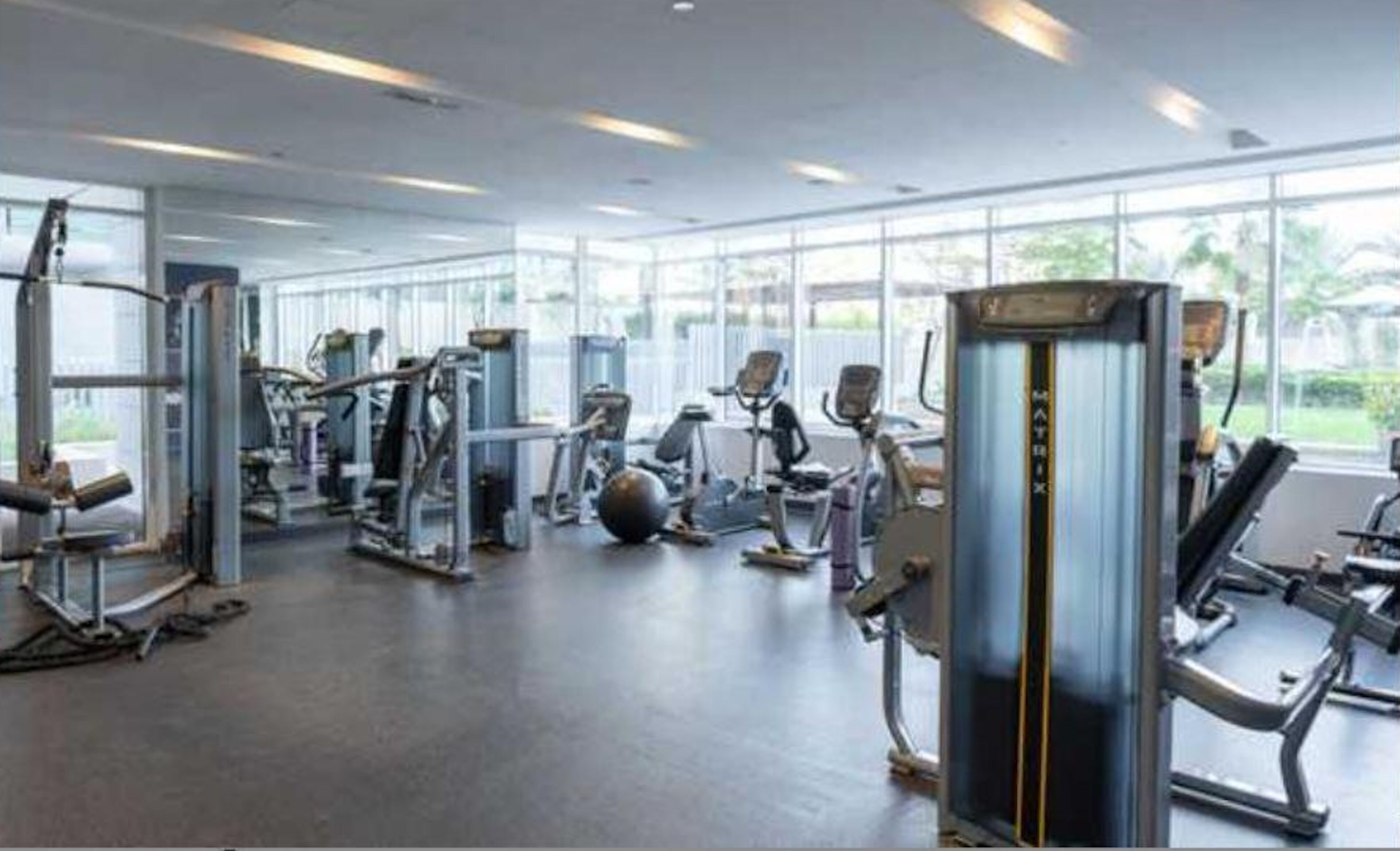 A gym with various exercise equipment, large windows, and a modern design.