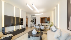 Ein modernes Wohnzimmer mit Flachbildfernseher, Essbereich und Küche.