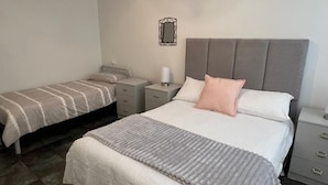 Une chambre à coucher avec un grand lit, un lit plus petit, des tables de chevet, un miroir et une commode.